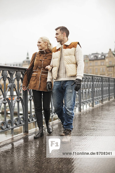 Full length of young couple walking on bridge