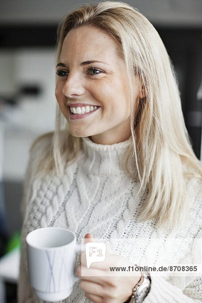 Lächelnde Geschäftsfrau mit Kaffeetasse im Büro