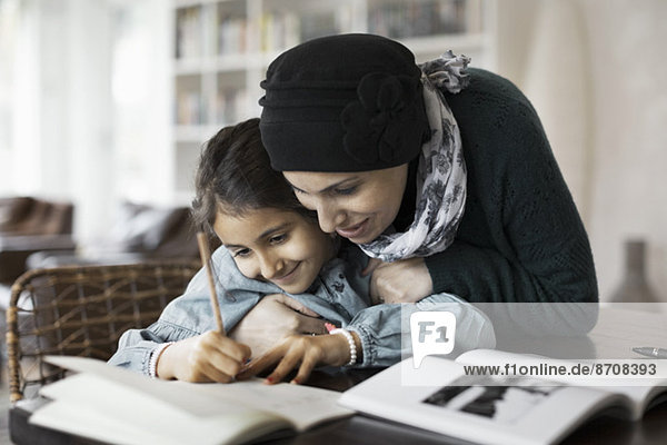 Mutter umarmt Tochter beim Lernen zu Hause