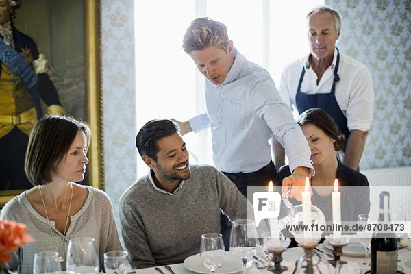 Kellner serviert Wasser für Geschäftsleute im Restaurant mit Chefkoch im Hintergrund
