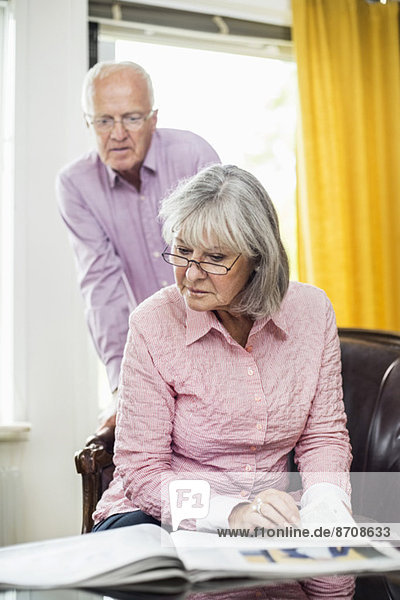 Seniorenpaar beim Zeitungslesen zu Hause