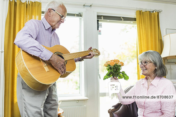 Senior Mann spielt Gitarre für Frau zu Hause