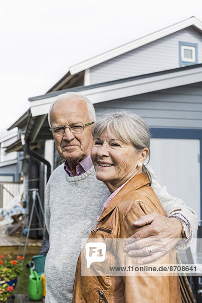 Porträt eines liebenden älteren Paares  das gegen das Haus steht