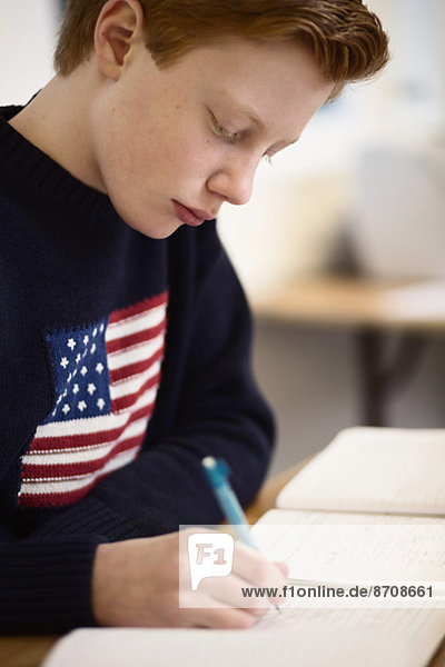 High school boy writing at desk in classroom