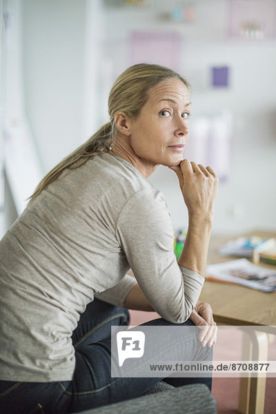 Portrait of businesswoman with hand on chin sitting in creative office