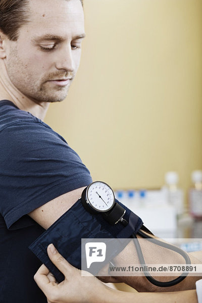 Arzt legt Blutdruckmanschette auf den Arm des Patienten in der Klinik