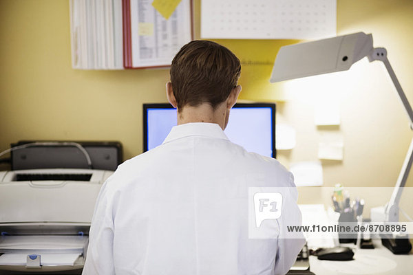Rückansicht eines männlichen Arztes mit Computer in der Klinik