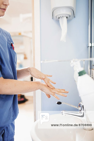 Side view of young nurse washing hands in hospital bathroom