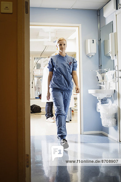 Full length of young female nurse walking in hospital corridor