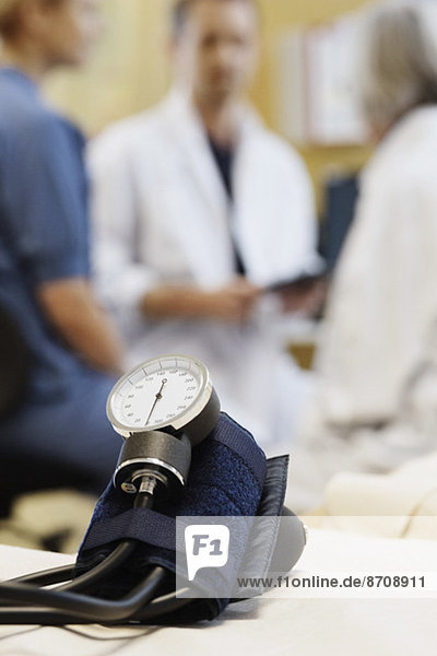 Blutdruckmessgerät mit medizinischem Team diskutiert im Hintergrund