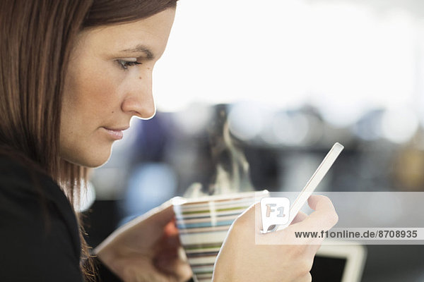 Geschäftsfrau SMS bei Kaffee im Büro