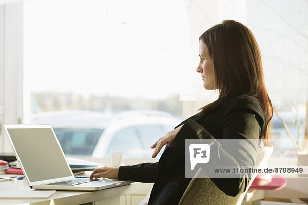 Side view of businesswoman working on laptop at desk