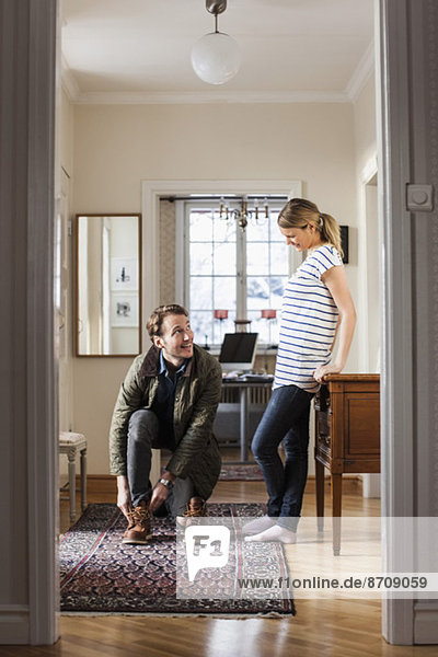 Man wearing shoes while looking at woman in house