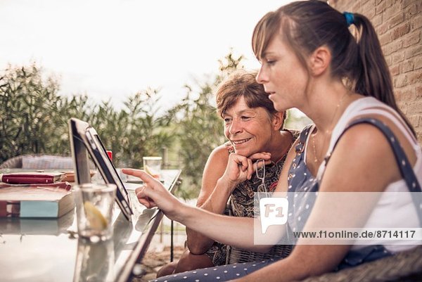 Mutter und mittlere erwachsene Tochter beim Betrachten des digitalen Tabletts