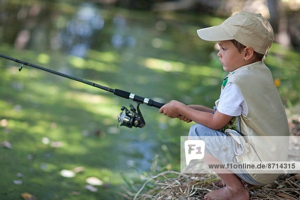 Boy fishing by stream