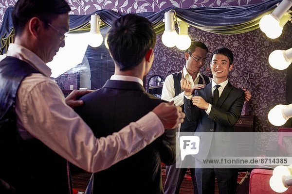 Schneiderin mit jungem männlichen Kunden beim Anprobieren eines neuen Anzuges im traditionellen Geschäft