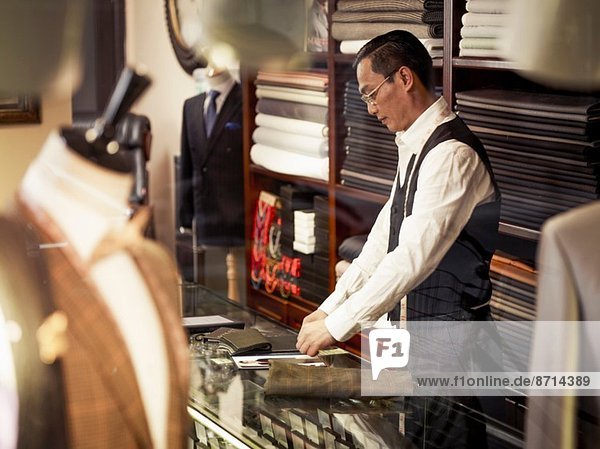 Tailor working at counter in tailors shop