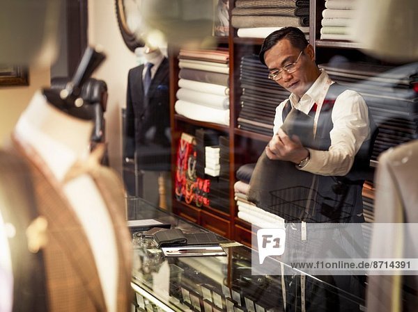 Tailor looking at fabric in traditional tailors shop