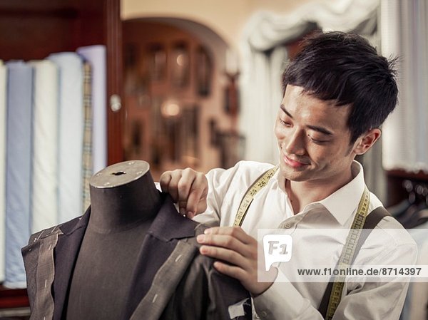 Trainee tailor pinning garment in traditional tailors shop