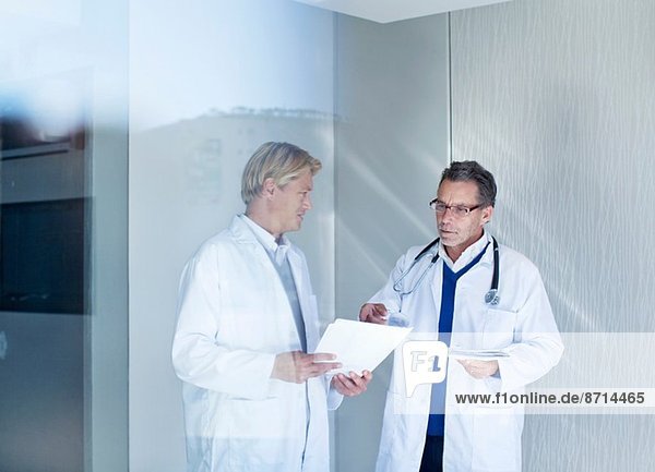Two male doctors discussing medical notes