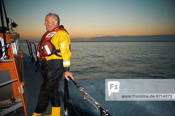 Portrait of mature man holding lifeboat railing at sea