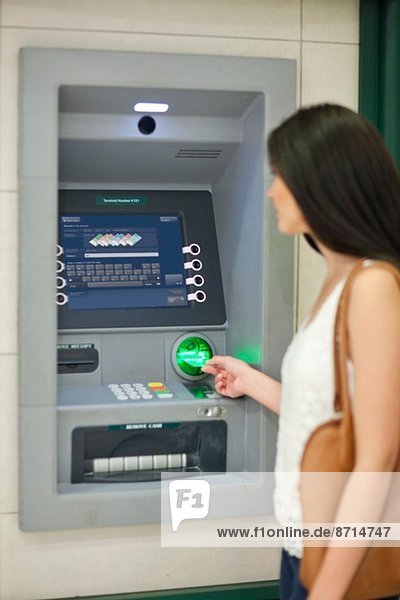 Junge Frau zieht Geld bei Geldautomaten