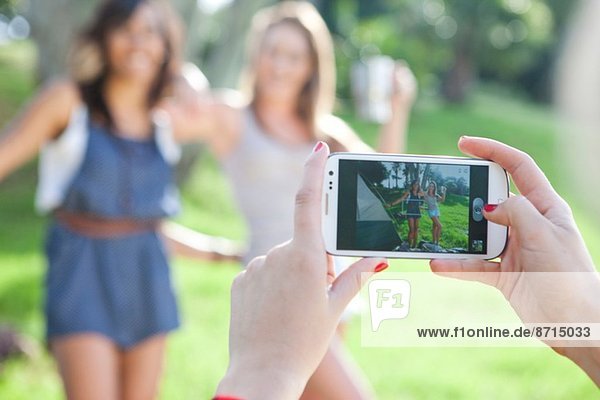 Drei junge Freundinnen beim Fotografieren mit dem Smartphone