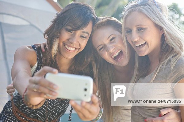 Three young female friends taking a selfie with smartphone