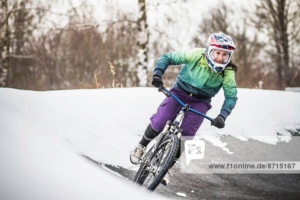 Young female mountain biker riding in snow