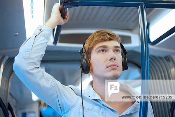 Junger Mann im Zugwagen hört Kopfhörer