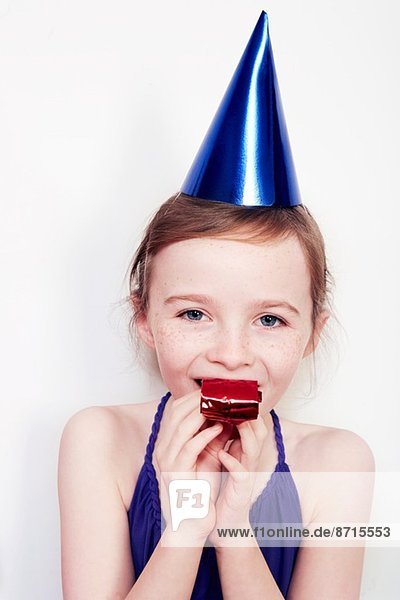 Porträt eines Mädchens mit Partybläser mit Partyhut