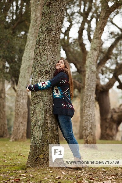 Junge Frau umarmt Baum im Wald