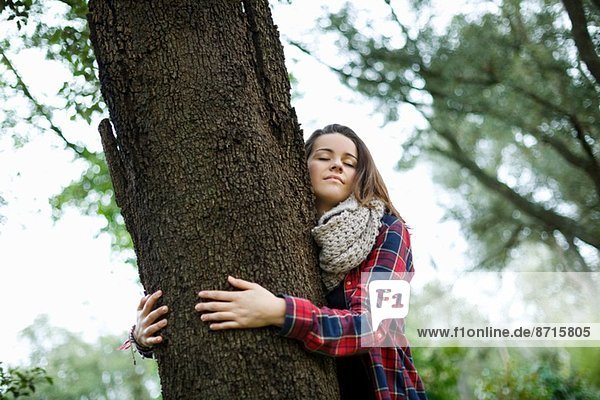 Teenagermädchen umarmt Baum im Wald