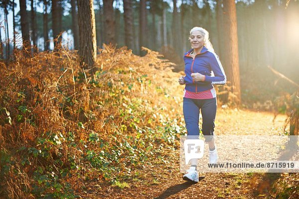 Mature woman jogging on forest path