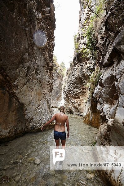 Young woman paddling in stream between rock formation  Costa del Sol  Spain
