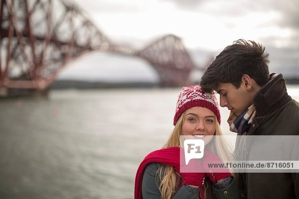 A young couple pose in front of the Forth Rail Bridge in Queensferry  near Edinburgh  Scotland