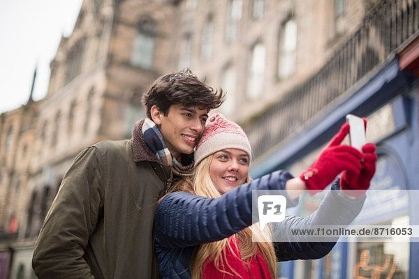 A young couple photograph themselves in the Grassmarket in Edinburgh  Scotland