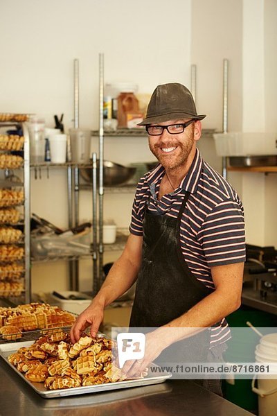 Male baker with tray of waffles in bakery