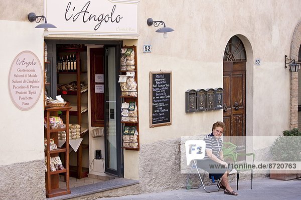 Außenaufnahme  sitzend  Frau  Lebensmittel  Laden  Delikatessen  Italien  Montalcino  Toskana  Val d'Orcia
