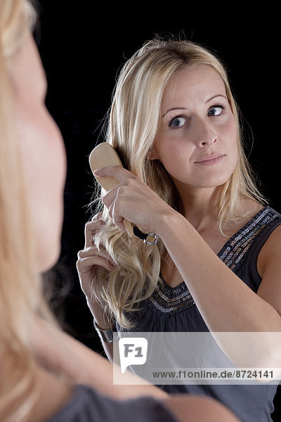 Junge Frau  Spiegelbild  blonde Haare bürstend