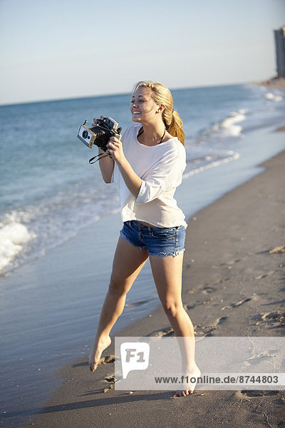 Young Woman Taking Pictures at Beach with Camera  Palm Beach Gardens  Palm Beach  Florida  USA