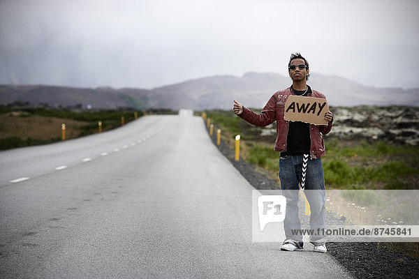 Young Man Hitchhiking with Cardboard Sign Iceland