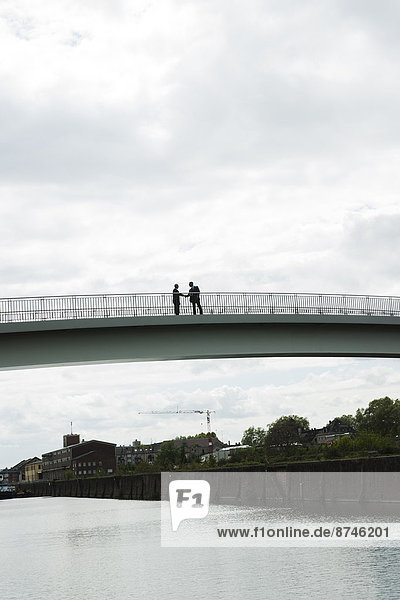 Silhouette of mature businessmen standing on bridge shaking hands  Mannheim  Germany