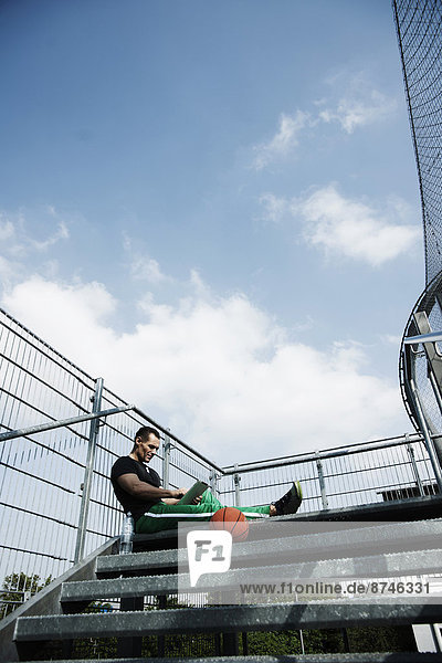 Stufe  sitzend  Mann  Computer  sehen  hoch  oben  reifer Erwachsene  reife Erwachsene  Basketball  Außenaufnahme  Gericht  Deutschland