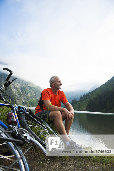 Mature Man Sitting by Lake with Mountain Bike  Vilsalpsee  Tannheim Valley  Tyrol  Austria