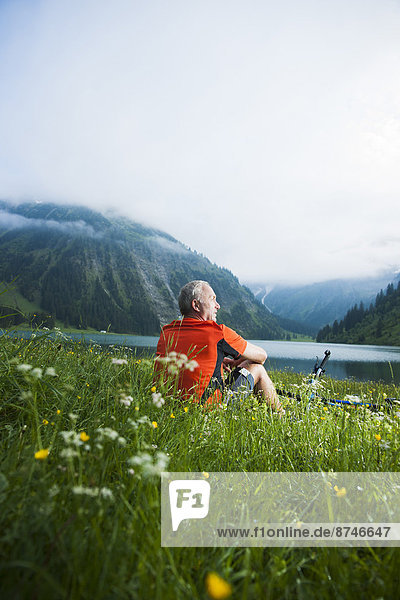 Mature Man with Mountain Bike sitting by Lake  Vilsalpsee  Tannheim Valley  Tyrol  Austria