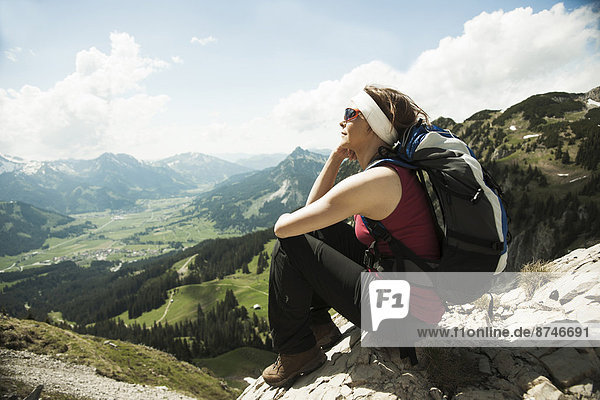 Mature woman sitting on cliff  hiking in mountains  Tannheim Valley  Austria