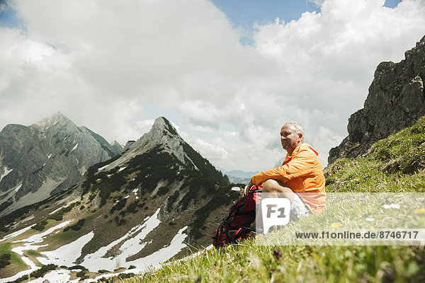 Mature man sitting on grass  hiking in mountains  Tannheim Valley  Austria