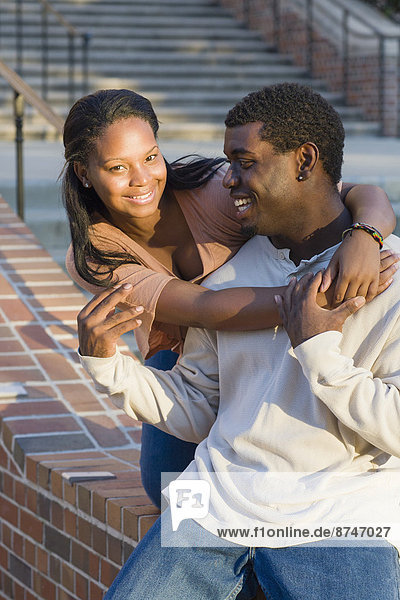 Young couple embracing outdoors on college campus  young woman smiling and looking at camera  Florida  USA