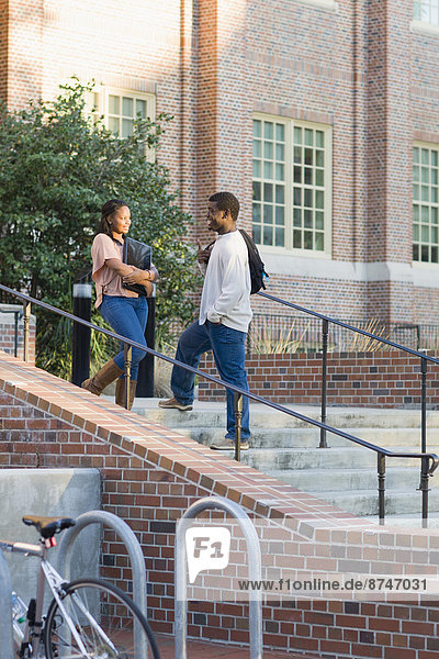 Young man and young woman outdoors on college campus  talking on stairs  Florida  USA